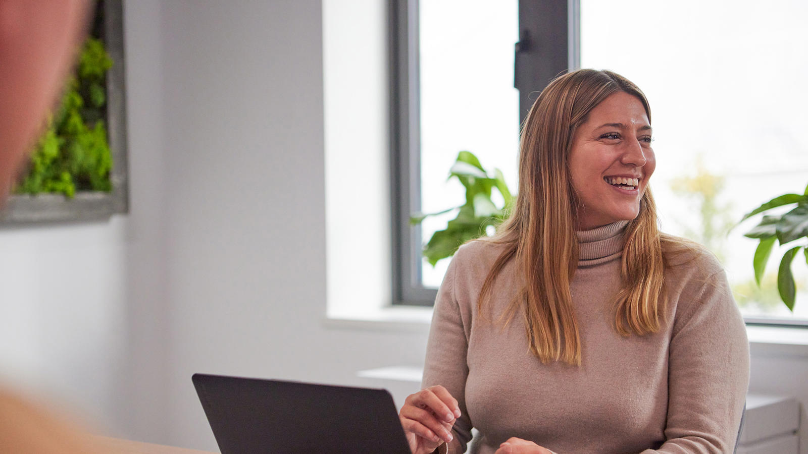 a woman smiling at a laptop