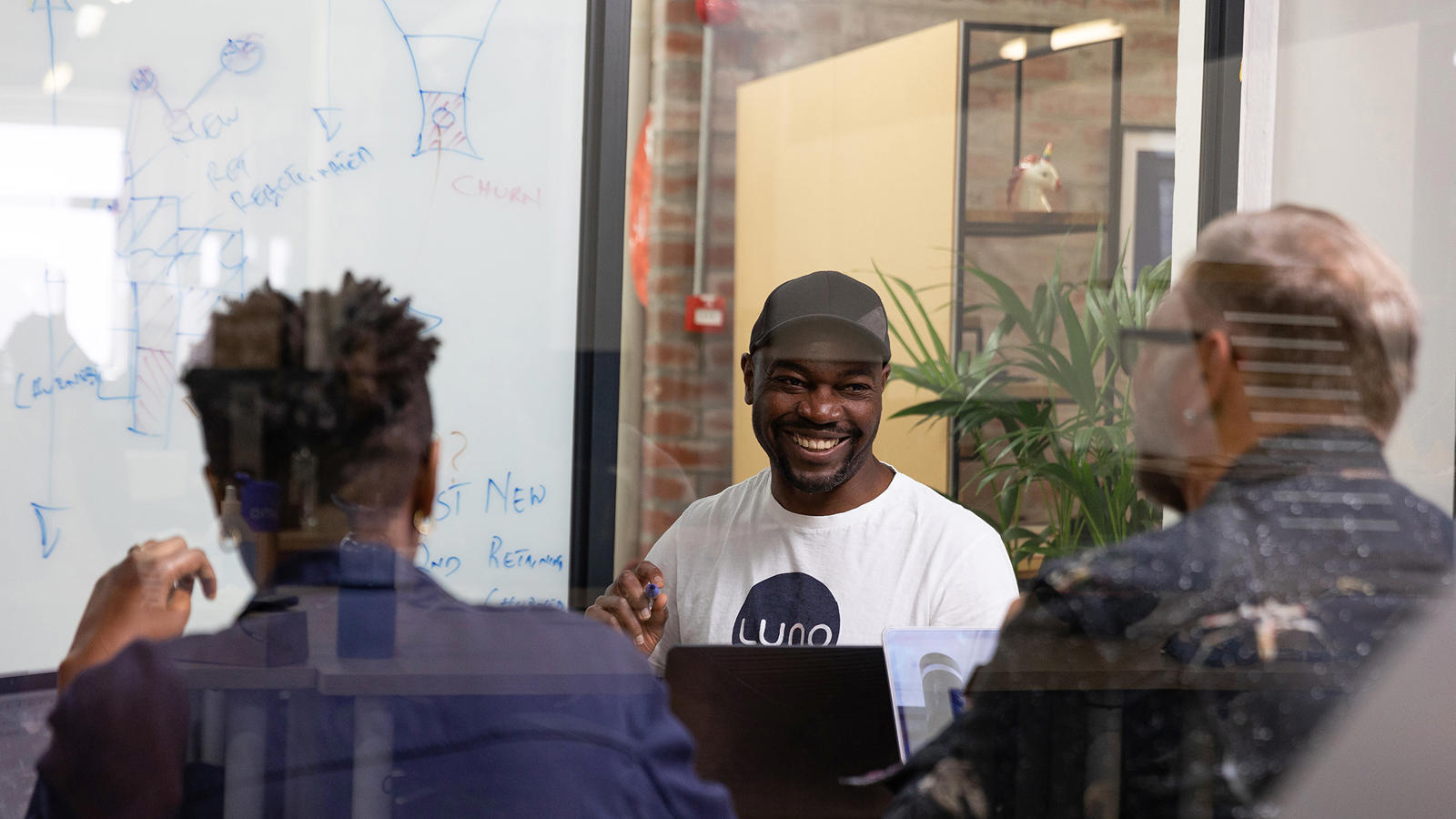 a man sitting at a table with a laptop and other people in the background
