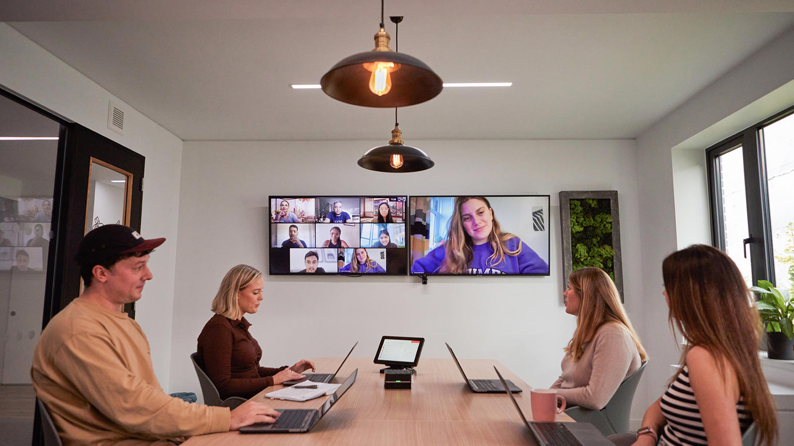 a group of people sitting at a table with laptops